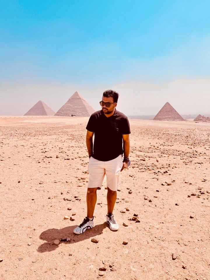 Traveler stands in desert with several pyramids aligned in background