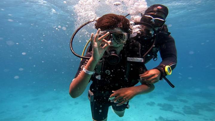 Underwater photo of diver giving OK sign with instructor in clear blue water