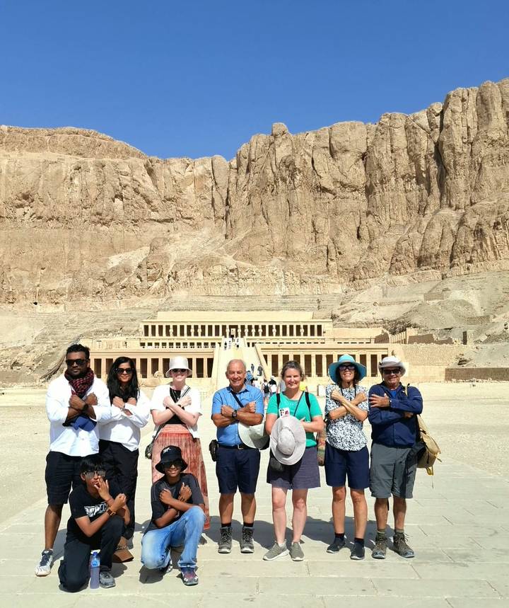Tour group posing with crossed arms before Hatshepsut Temple terraces