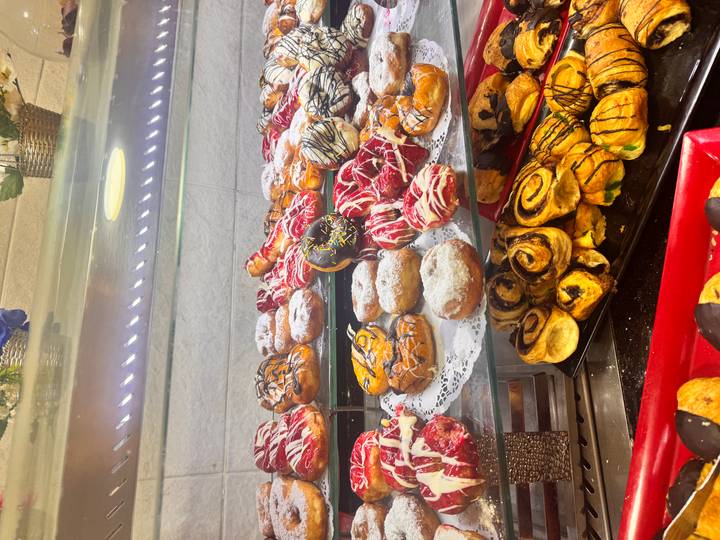 Bright glass display of assorted colourful pastries and donuts in bakery