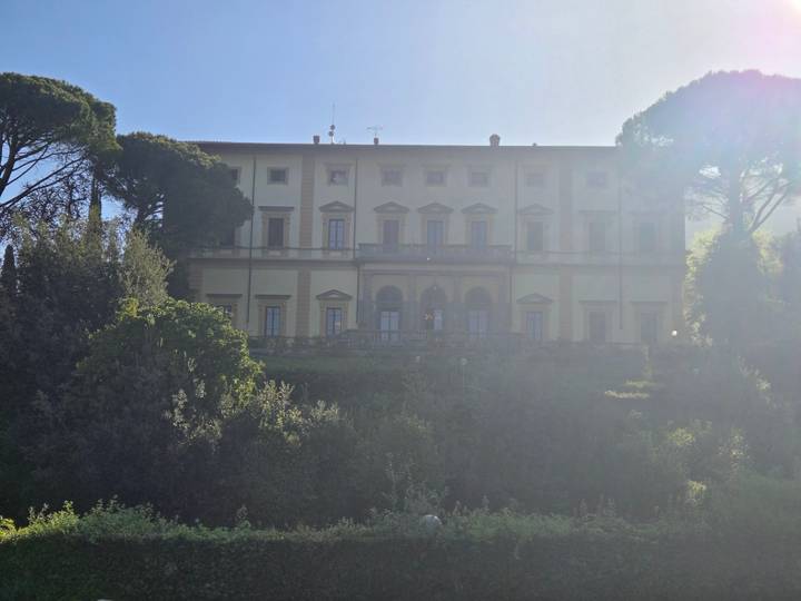 Historic villa façade partially in shadow with surrounding greenery