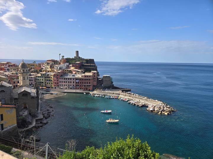 Panoramic view of Vernazza harbor with colorful buildings and boats on deep blue Ligurian Sea