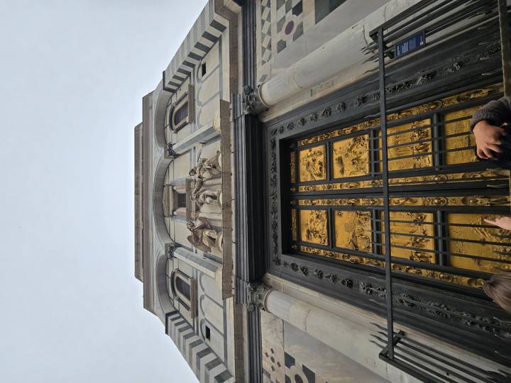 Upward view of the gilded Gates of Paradise on Florence Baptistery with visitors below