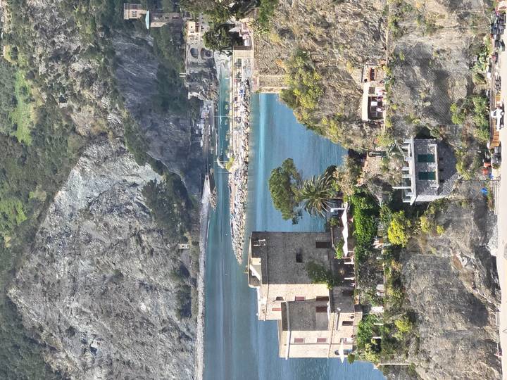 Rocky coastline and turquoise bay with stone towers and greenery in Cinque Terre
