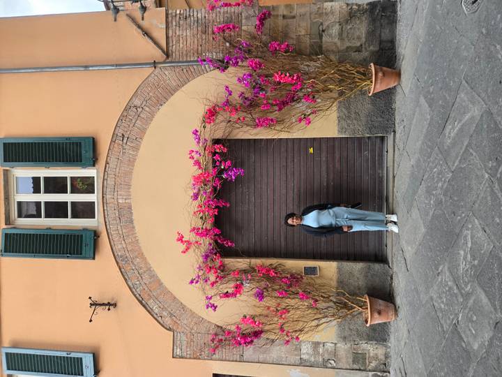 Woman posing in front of a wooden door framed by bright pink bougainvillea