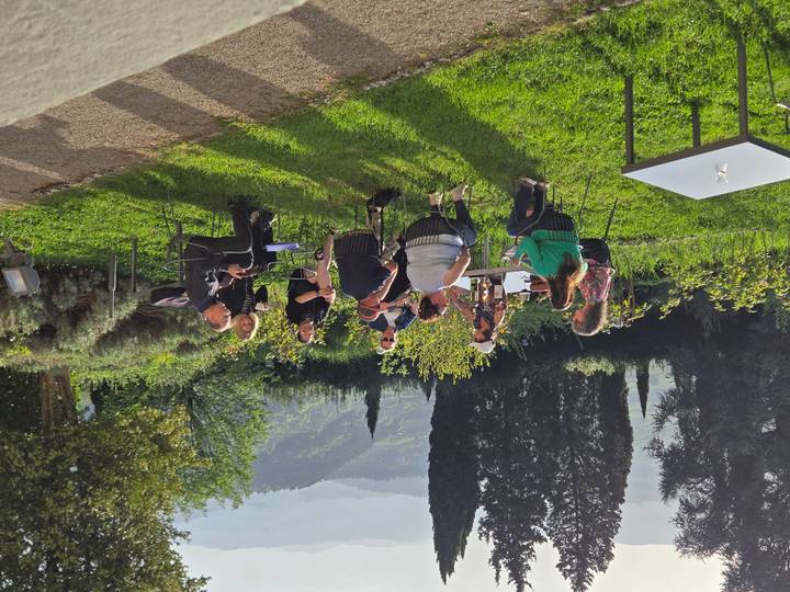 Small group enjoying drinks at outdoor tables overlooking green Tuscan hills
