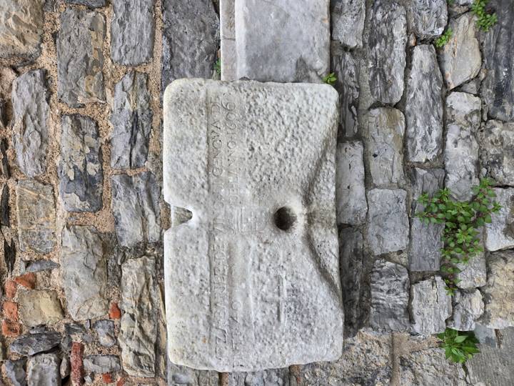 Weathered marble trough inset in a stone wall with faint historic inscription