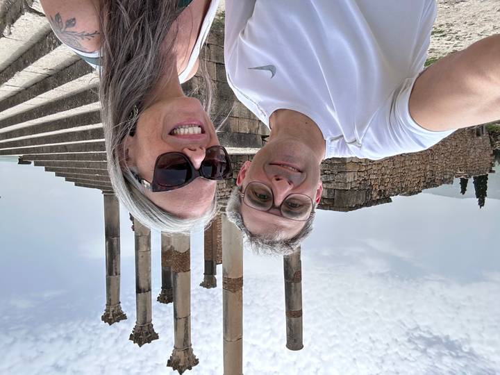 Selfie of a couple at the Roman ruins of Volubilis with tall columns in the background.
