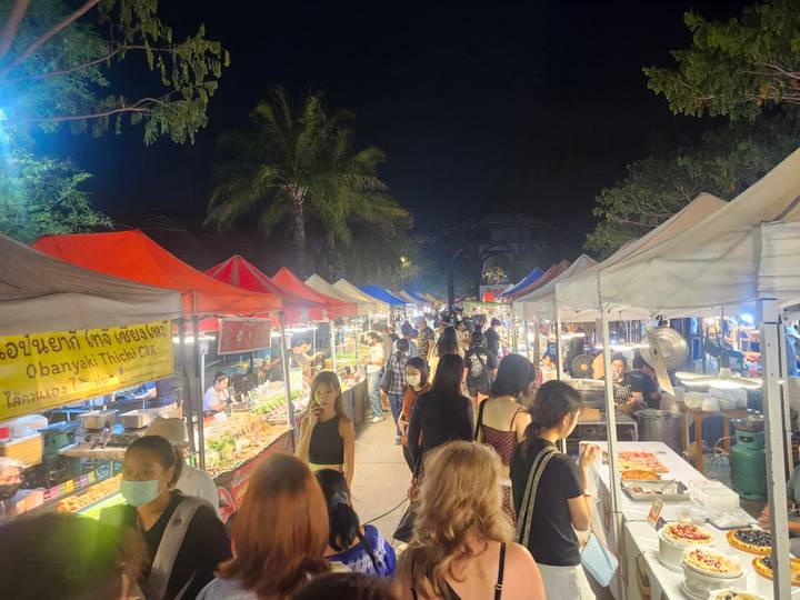 Bustling night market lined with colorful tents and food stalls packed with visitors