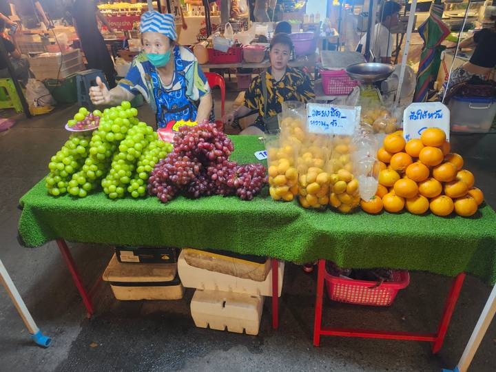 Fruit stall displaying piles of grapes and oranges at a night market