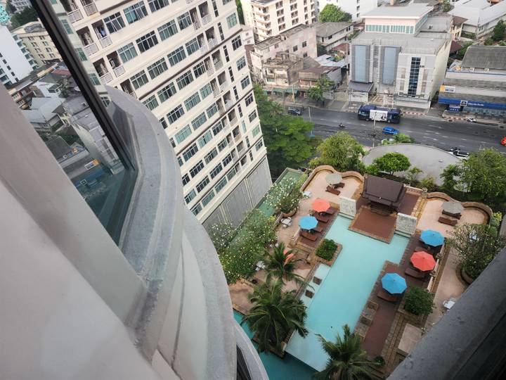 High-rise city view looking down onto a rooftop swimming pool with colorful umbrellas
