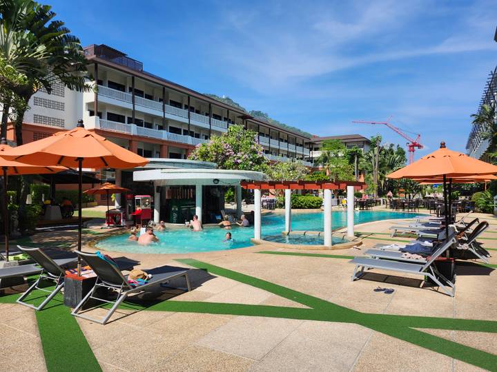 Resort swimming pool with swim-up bar, orange umbrellas and lush tropical setting