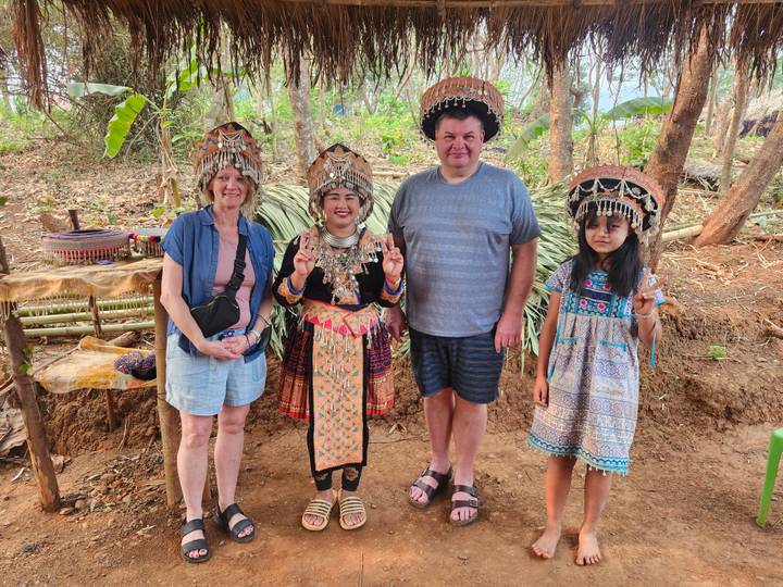 Tourists posing with local hill-tribe hosts wearing traditional ornate headdresses