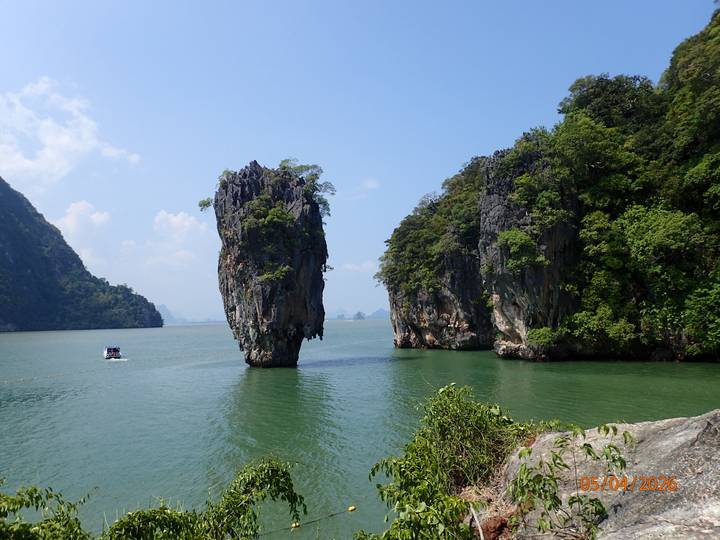 Iconic limestone stack James Bond Island rising out of emerald green water