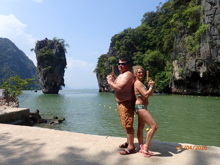 Couple striking James Bond pose in swimsuits with limestone island backdrop