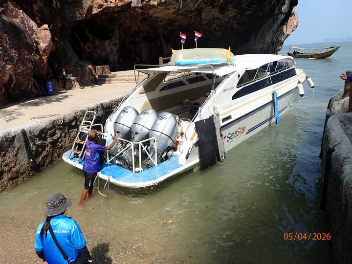 Speedboat docked in a rocky cove with crew member securing the bow