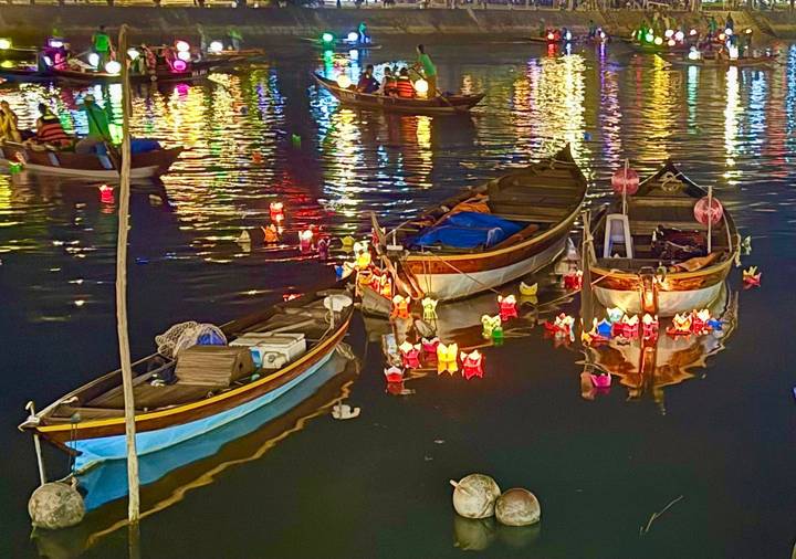 Night scene of small wooden boats surrounded by colorful floating lanterns on the river