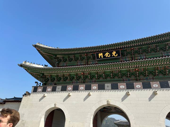 Detailed view of the ornate roofline and signboard of Gwanghwamun Gate under clear sky.