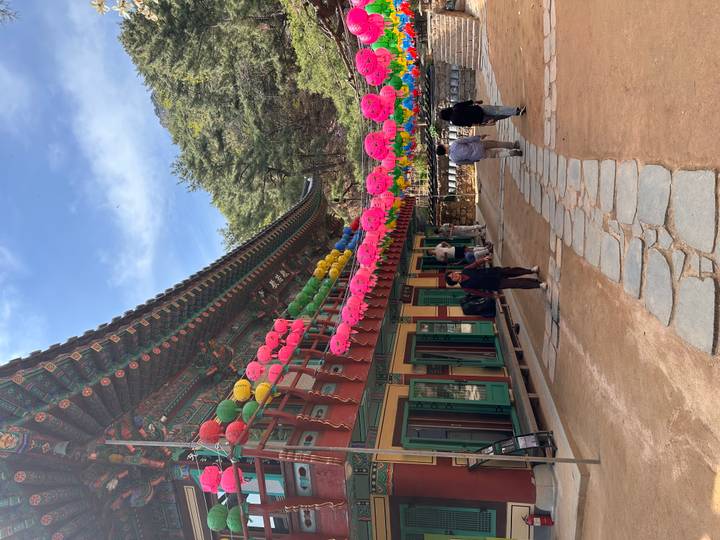 Mountain temple courtyard decorated with rows of colourful lanterns as visitors explore the grounds.