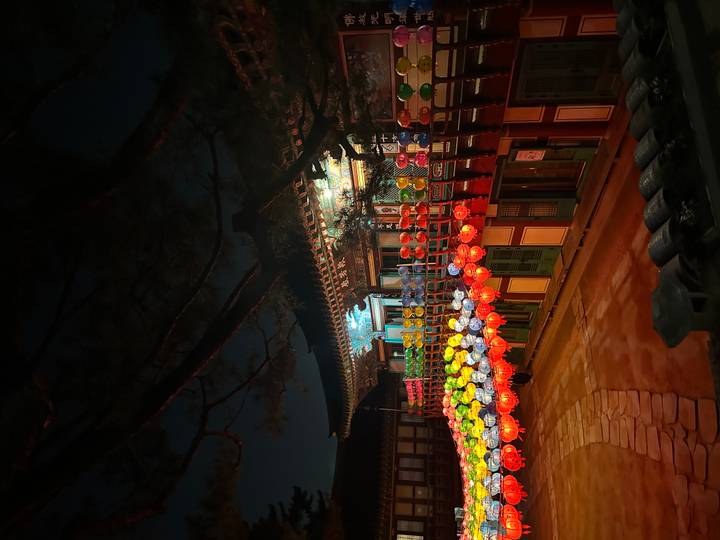 Traditional Korean building decorated with colorful lanterns glowing at night.