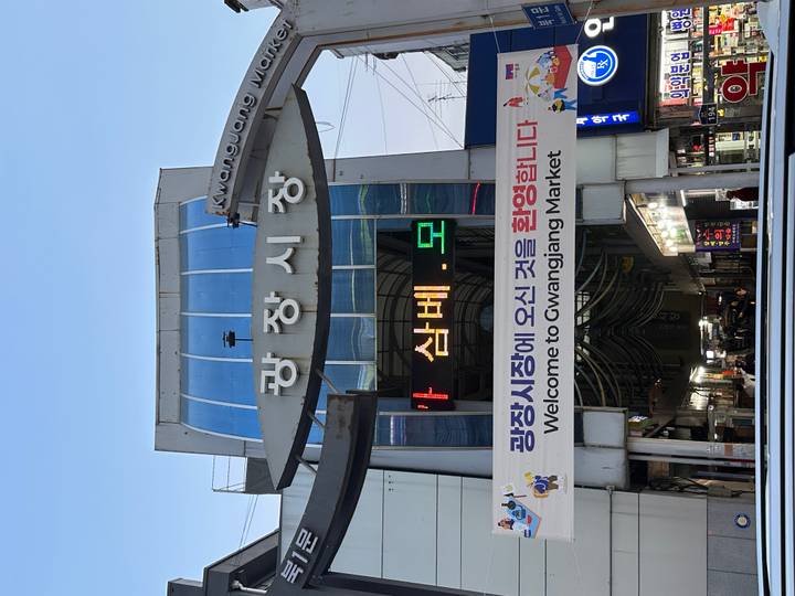 Entrance of Gwangjang Market with bold Korean signage and LED welcome banner.
