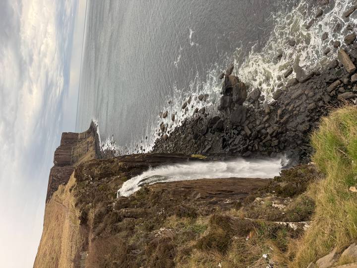 Dramatic coastal waterfall plunging from basalt cliffs into the sea on the Isle of Skye.