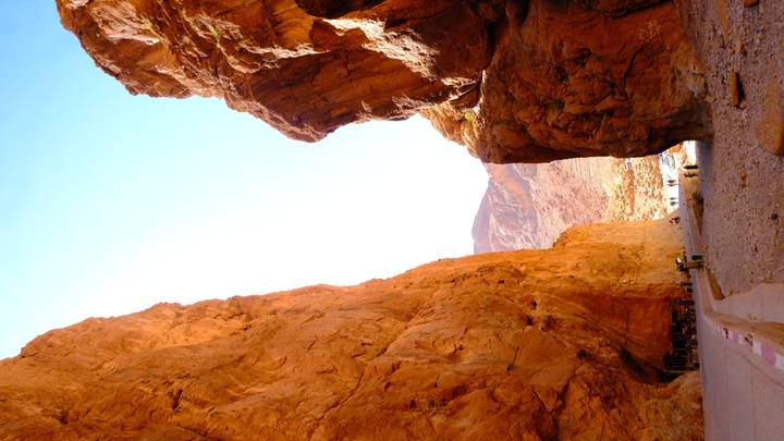 Towering orange canyon walls of Todra Gorge rising above a narrow winding road