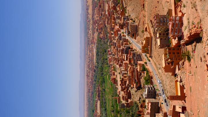 Expansive view of an arid valley town with green oasis patches under clear blue sky