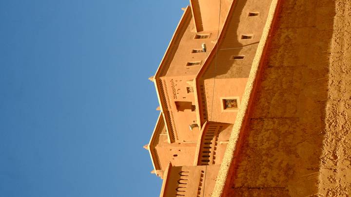 Adobe-style earthen fortifications set against a deep blue Moroccan sky
