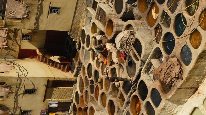 Traditional leather tannery with circular dye pits and workers at Fes