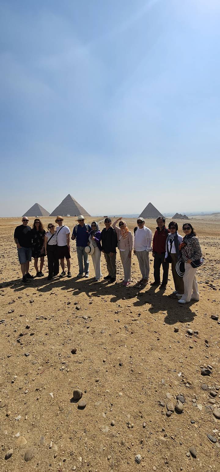 A tour group poses before the three iconic pyramids rising from the Giza Plateau.
