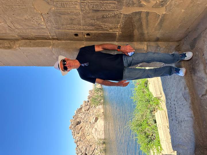 Man in hat posing in same temple doorway with Nile backdrop.