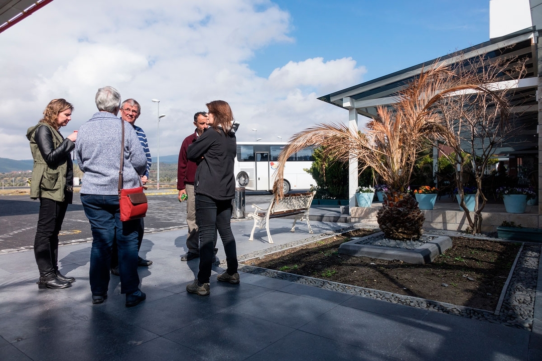 Group of people talking outside near a parked bus.