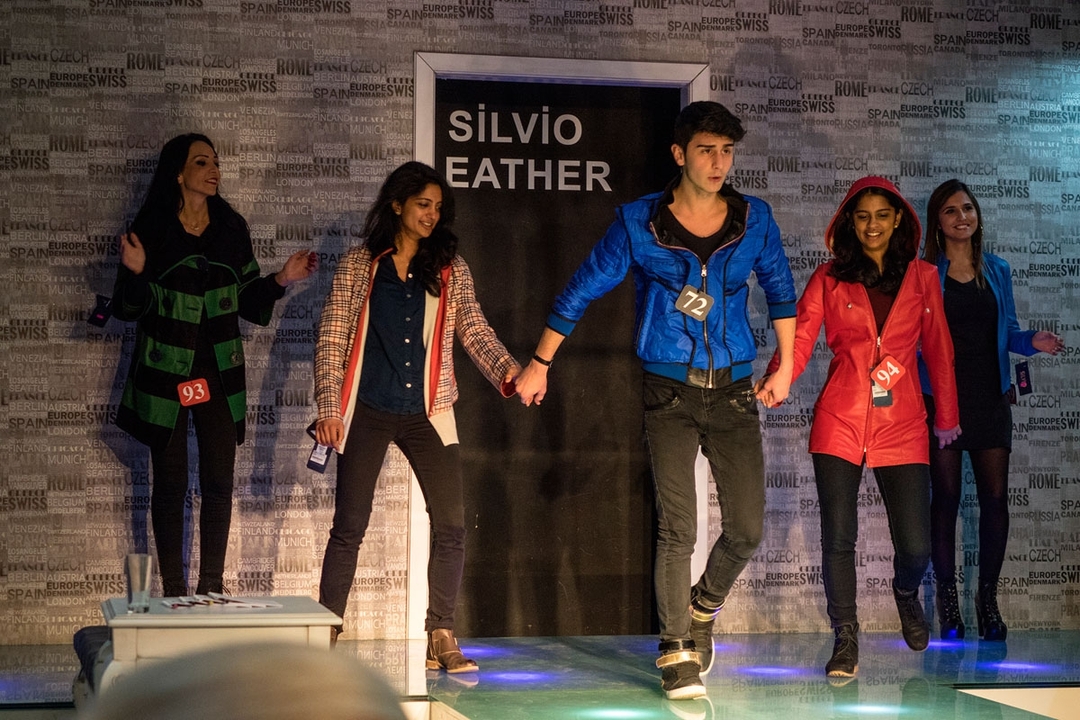 Fashion show with models holding hands on stage.