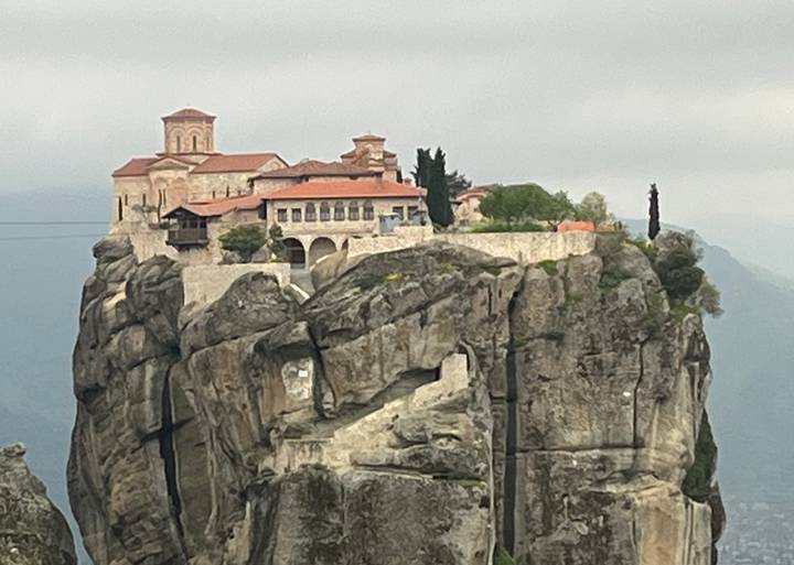 Historic monastery crowns a rocky pinnacle under grey skies in Meteora.