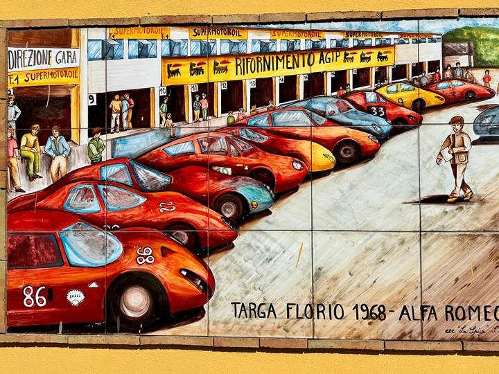 Colorful mural depicting classic racing Alfa Romeo cars in a pit lane scene.