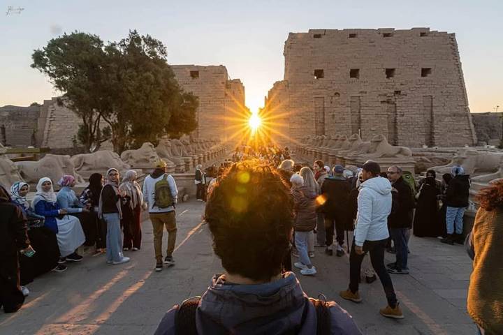 Crowds line the Avenue of Sphinxes at Karnak as the sun sets precisely between temple pylons.