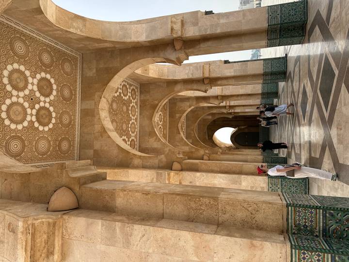 Visitors pause for photos along the ornate corridor of Hassan II Mosque.
