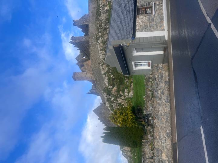 Distant ruined hilltop fort seen beyond village buildings and wet roadside.