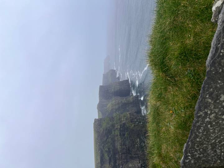 Misty cliffs drop to crashing Atlantic waves along the Cliffs of Moher.