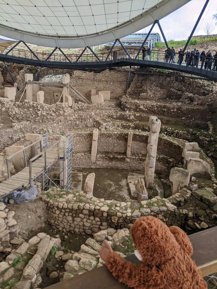Stone enclosures and tall T-shaped pillars at the archaeological site of Göbekli Tepe under protective roofing.