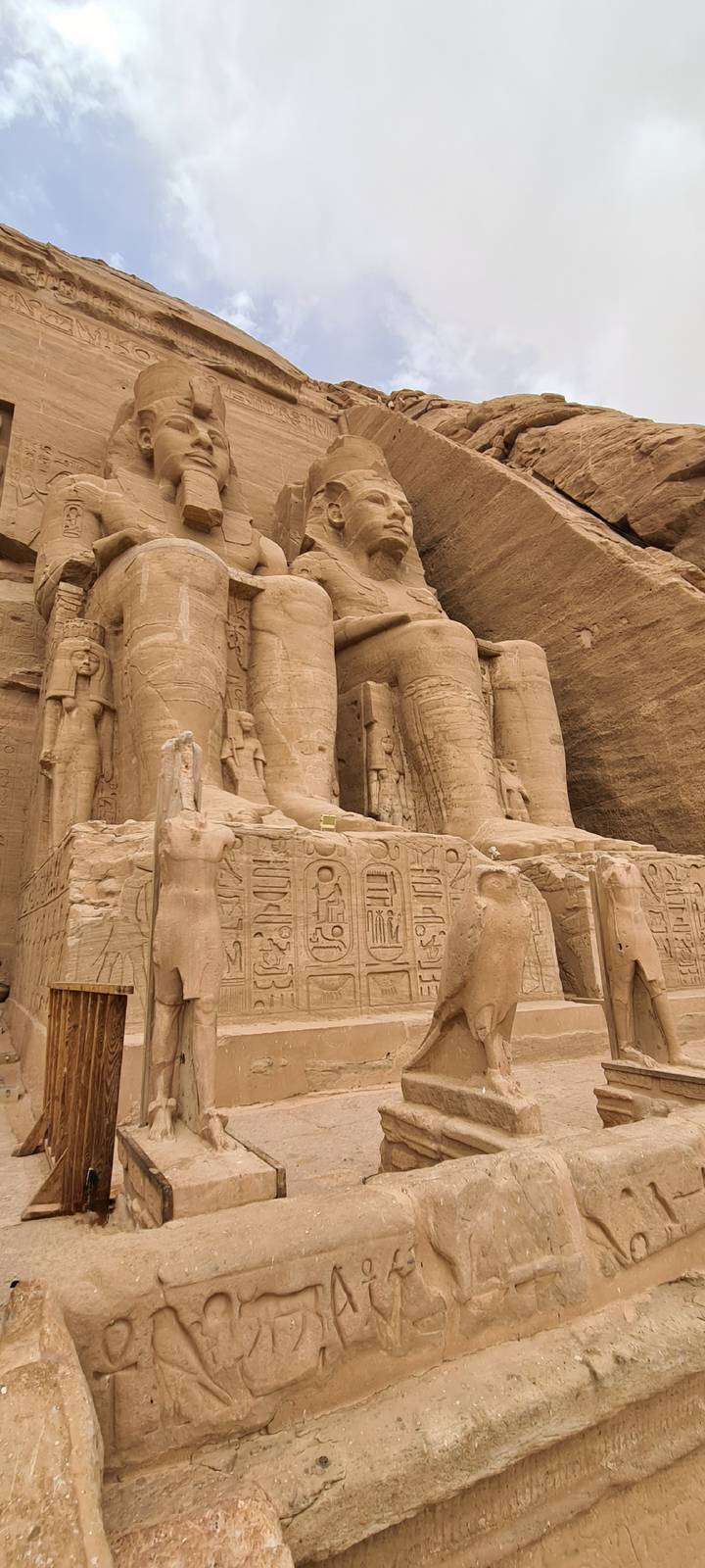 Close details of seated pharaoh statues and hieroglyphs carved into the sandstone facade of Abu Simbel