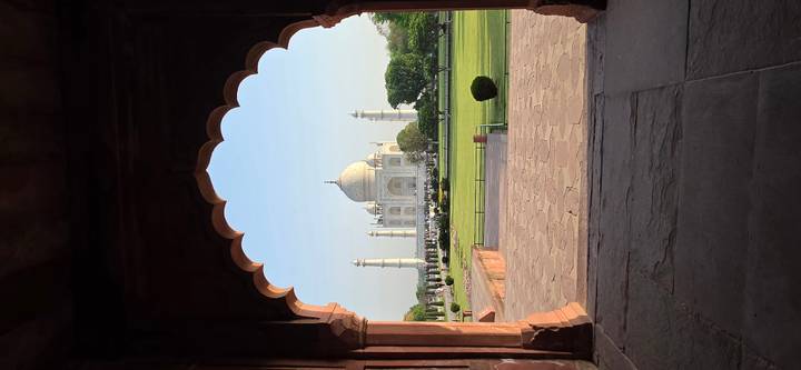 The Taj Mahal perfectly framed by a Mughal archway in soft morning light.