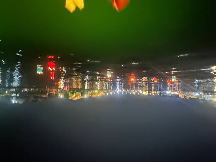 Blurry night shot of colourful lantern reflections shimmering on a riverfront town.