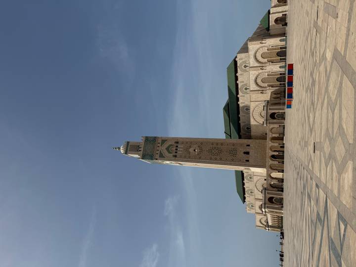 Majestic Hassan II Mosque rises over a vast marble courtyard beneath a hazy sky in Casablanca