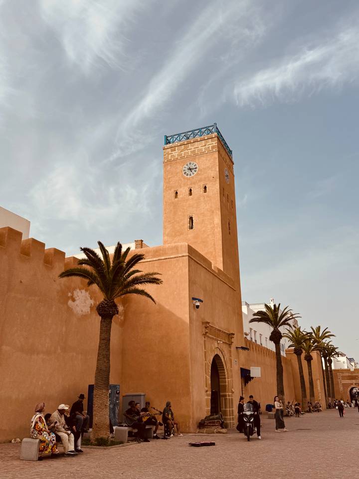Ochre clock tower and fortress walls framed by palm trees in the coastal town of Essaouira