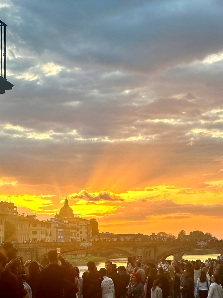 Dramatic golden rays burst through clouds over a silhouetted city skyline at sunset