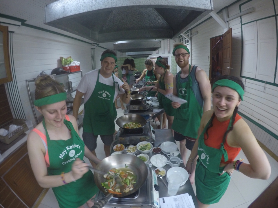 Group of people in a cooking class, wearing aprons and headbands.
