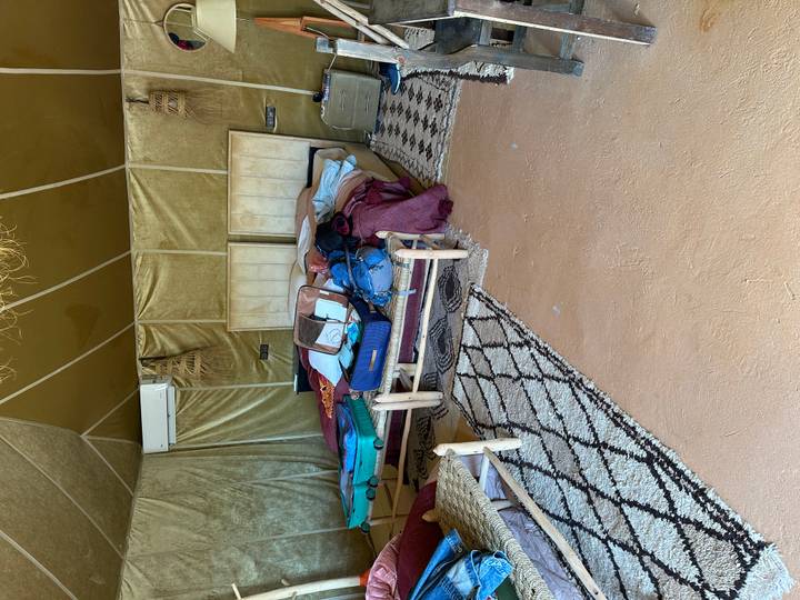 Inside a desert camp tent with unmade twin beds and scattered suitcases