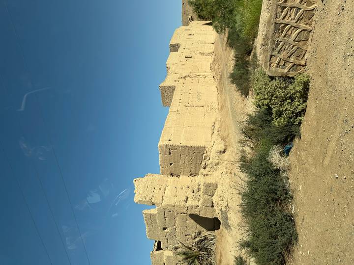 Crumbling adobe fort walls stand against a clear blue desert sky
